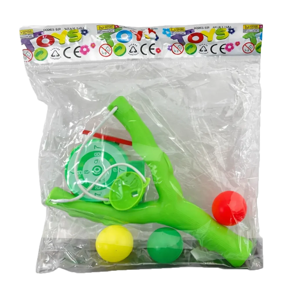 Toy slingshot set with green plastic slingshot, three colorful balls, and small target game in clear retail bag packaging.