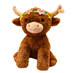 Brown highlander cow plush with soft fur, beige horns, and a colorful flower crown, sitting on a white background.