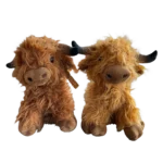 Two plush highland cattle with long brown coats and dark horns, sitting next to each other against a white background.