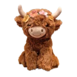 Brown Highland cow plush with long soft fur, cream horns, and a colorful flower crown on its head