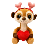 Cute plush meerkat holding a red heart, with pink antlers and a red headband, isolated on a clean white background.