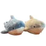 Two assorted shark plush toys displayed side by side on a light background, featuring one blue shark and one grey shark with soft fabric, embroidered eyes, white ribbed bellies, and friendly smiling faces.