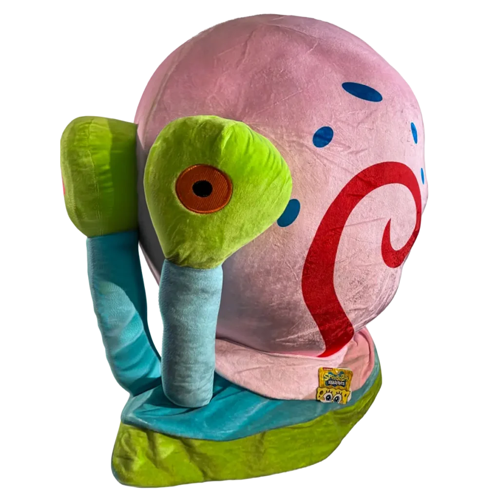 Large plush snail inspired by a popular cartoon character, featuring a soft pink shell with blue spots and a red swirl pattern. The snail has bright green eye stalks, a blue body, and embroidered details, sitting upright against a white background.